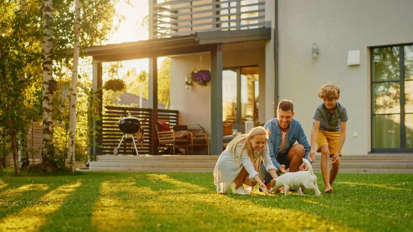 Family playing with their dog in a sunny backyard